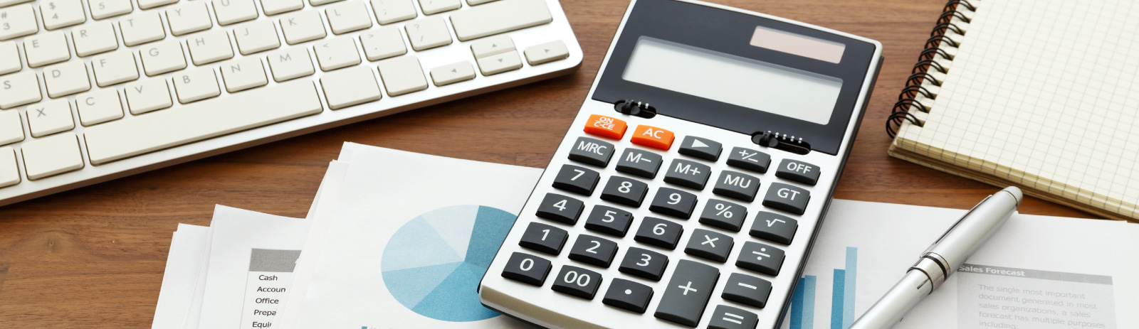 a calculator placed next to a writing pen, a day planner, and a computer keyboard