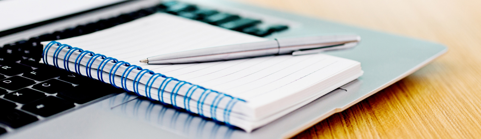 a note pad and writing pen on a computer keyboard